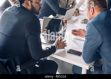 Nahaufnahme, Ansicht von oben zuversichtlich Business Männer verschiedener Rasse und Alter, zusammen arbeiten, Menschen auf der Suche nach Bauplan, Reden, mit Laptop duting meeti Stockfoto