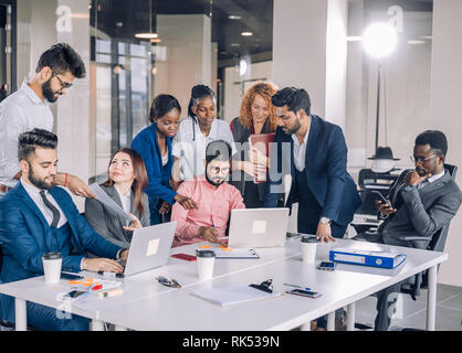 Die Suche nach neuen Erkenntnissen und geniale Ideen. Mixed-Race Gruppe von neun unterschiedlichen Menschen surfen im Netz und suchen durch Dokumente während der Sitzung am Stockfoto