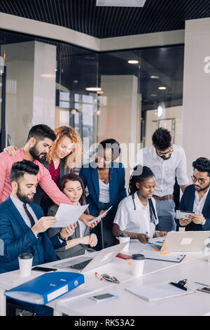 Die Suche nach neuen Erkenntnissen und geniale Ideen. Mixed-Race Gruppe von neun unterschiedlichen Menschen surfen im Netz und suchen durch Dokumente während der Sitzung am Stockfoto