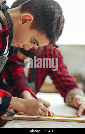 Neugierige kleine Junge Klassen der Tischlerei aus berühmten WOODWORKER. Hobby wächst in der Arbeit von Berufung. Stockfoto