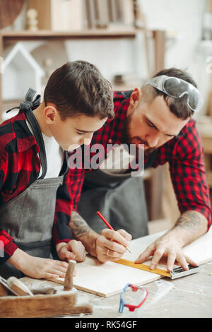 Neugierige kleine Junge Klassen der Tischlerei aus berühmten WOODWORKER. Hobby wächst in der Arbeit von Berufung. Stockfoto