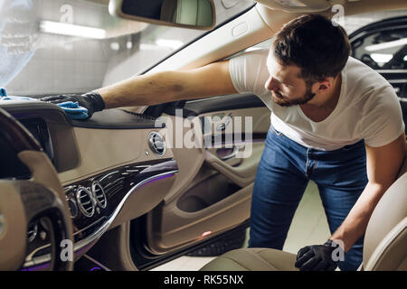 Super Elegante mann Reinigung der verschmutzten Fahrzeugs. nach oben Foto schliessen. Job, Beruf Stockfoto