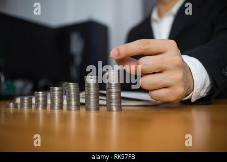 Geschäftsmann nimmt Münzen auf den Tisch und zählt Geld. Geschäftskonzept. Stockfoto