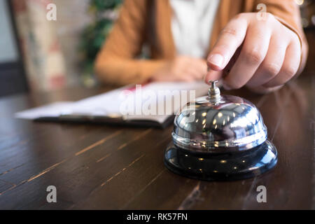 Frauen rufen Sie das Hotel an der Rezeption mit dem Finger drücken Sie eine Glocke in der Lobby Hotel. hotel Konzept. Stockfoto