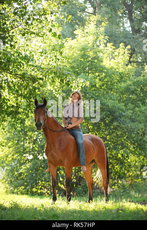 Schöne cowgirl Bareback ihr Pferd im Wald Lichtung bei Sonnenuntergang Stockfoto