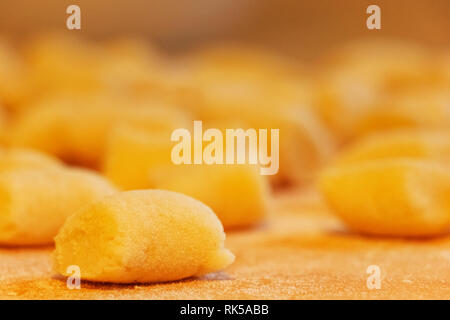 Dick und Kleine handgemachte Gnocchi - Teig Knödel - auf einem Holzbrett, unscharf Hintergrund Stockfoto