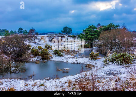 Landschaft Foto von kleinen alten Steinbruch Grube auf canford Heide im Schnee, Poole, Dorset, Großbritannien. Stockfoto