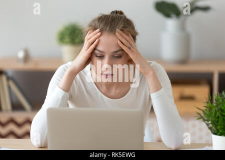 Junge Frau mit Laptop lesen schlechte Internet Nachrichten betonte Stockfoto