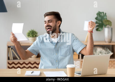 Glückliche junge Mann aufgeregt Lesen gute Nachrichten, E-Mails schreiben Stockfoto