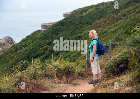 Frau Wanderer mit Blick auf das Meer durch die Versteckten WW 2 Deutsche Concreate Beobachtungsbunker Jerbourg Point auf dem Küstenweg von Guernsey Kanalinseln Stockfoto