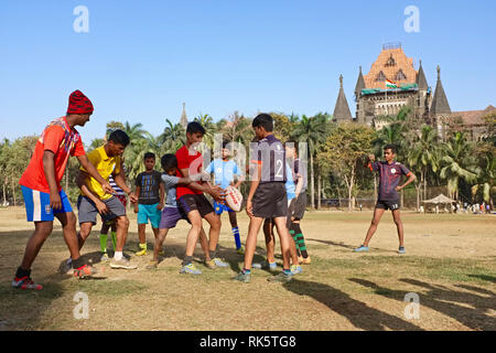 Kinder aus den Slums in Mumbai, Indien, treffen am Samstag auf der Stadt Oval Maidan Rugby zu spielen; im gelben Hemd: Der Trainer; b/g: Bombay High Court Stockfoto