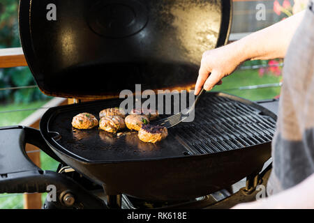 Man flipping Burger auf home Barbecue-grill. Stockfoto