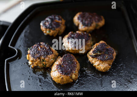 Kleine burger Pastetchen sizzling am Grill heiße Platte. Stockfoto