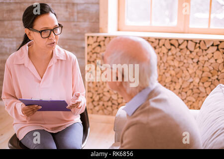 Aufmerksame internationale Frau im Pflegeheim arbeiten Stockfoto