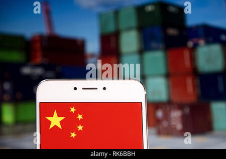 Hong Kong. 8 Feb, 2019. Chinesische Fahne ist auf ein Android mobile Gerät mit einer Umladung Containerhafen im Hintergrund zu sehen. Credit: Miguel Candela/SOPA Images/ZUMA Draht/Alamy leben Nachrichten Stockfoto