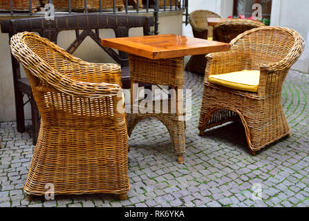 Korbstühlen und Tisch draußen im Innenhof Stockfoto