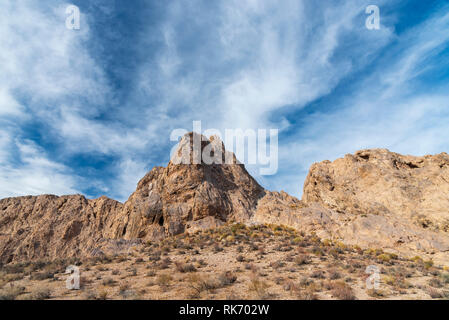 Desert Rock Formationen unter strahlend blauen Himmel mit Wind Wolken. Hohen felsigen Gipfel im Zentrum. Stockfoto