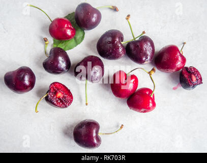 Rote Kirschen mit Stängel auf weißem Hintergrund verstreut Stockfoto