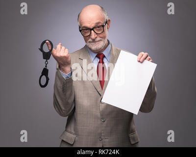 Senior Business-Mann mit Handschellen und leere Vertrag Papier Hinweise auf Gefahr der Wirtschaftskriminalität Stockfoto