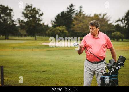 Älterer Mann herauf Golf Club aus der Tüte am Golfplatz. Reife männliche Golfspieler wählt seine Club für das nächste Spiel. Stockfoto