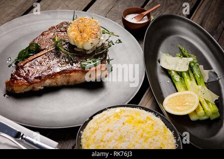 Saftiges, ungeschnittenes T-Bone Steak mit Spargel und handgefertigtem Kartoffelpüree. Stockfoto