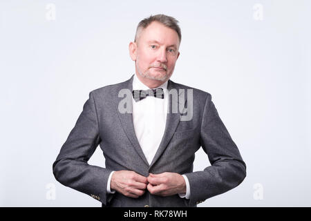 Zuversichtlich älterer Geschäftsmann in Anzug posiert lächelnd Stockfoto
