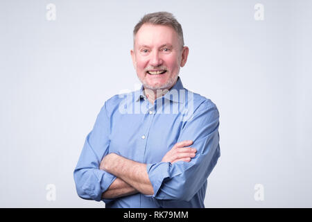 Älterer Mann im blauen Hemd breit grinsend Stockfoto