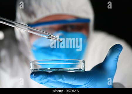 Männliche Chemiker Blick an Mikroskop halten Reagenzglas Stockfoto