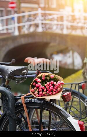 Blumenstrauß aus schönen rosa Tulpen liegen auf dem Stamm des Bike. Amsterdam Stockfoto