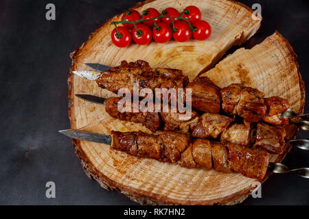 Shish Kebab am Spieß mit Tomate die schwarzen Holztisch. Stockfoto