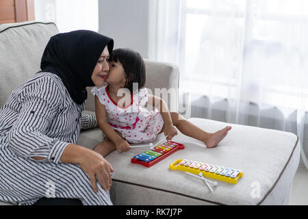 Granddaugther kiss Oma auf ein Küken beim zusammen zu Hause spielen Stockfoto
