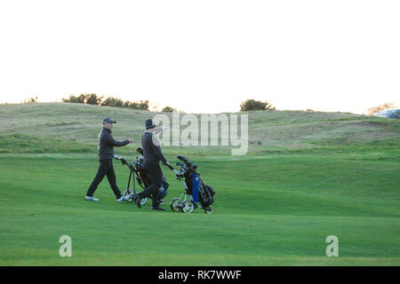 Zwei Männer drehen Wagen mit Ihrem Golf Taschen durch Grüns auf den Carton House Golf Kurs in Maynooth, County Kildare, Irland Stockfoto