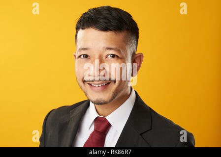 Headshot von lächelnden asiatischer Mann auf gelbem Hintergrund Stockfoto
