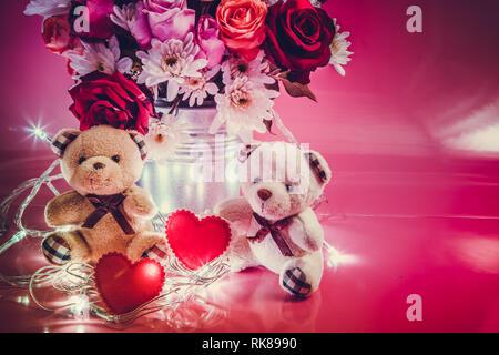 Paar schöne tragen und roten Herzen in der Nähe von Vase Blumenstrauß Rosen in Aluminium Schaufel auf rosa Hintergrund. Valentinstag Konzept. Stockfoto