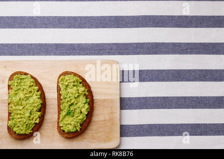 Guacamole Sandwich auf hellen Hintergrund avocado Sandwiches auf Holzbrett und textile Draufsicht Stockfoto