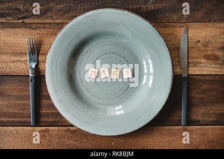 Ein Wort Diät aus einem Alphabet Fliesen in einem leeren Teller gemacht. Konzept der Diät, Abnehmen und gesunde Ernährung Stockfoto