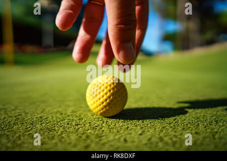 Minigolf gelbe Kugel auf grünem Gras bei Sonnenuntergang Stockfoto