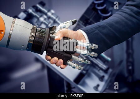 Hand eines Geschäftsmannes Händeschütteln mit einem Android Roboter. Das Konzept der menschlichen Interaktion mit der künstlichen Intelligenz. Stockfoto