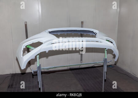 Reparatur des hinteren Stoßfängers, der ein weißes Auto nach einem Unfall mit Hilfe von mehrfarbigen Kitt in einem Workshop für die Lackierung von Fahrzeugen, die in einem speziellen chamb Stockfoto