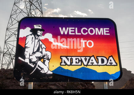 'Willkommen in Nevada' Zeichen (Flash lit) mit einem elektrischen Pylon hinter neben dem Hoover Dam, Nevada, United States. Stockfoto