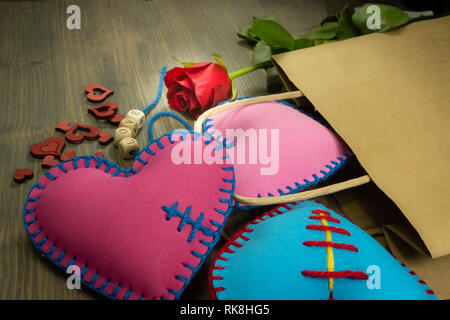 Papiertüte voller Herzen handgemachte Souvenirs, Rose und Liebesbriefe auf rustikalen Holzmöbeln Hintergrund. Liebe, Beziehung, Valentinstag, gebrochene Herzen anhand von quantitativen Simulatio Stockfoto