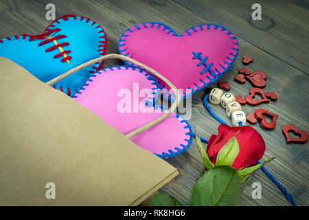 Papiertüte voller Herzen handgemachte Souvenirs, Rose und Liebesbriefe auf rustikalen Holzmöbeln Hintergrund. Liebe, Beziehung, Valentinstag, gebrochene Herzen anhand von quantitativen Simulatio Stockfoto
