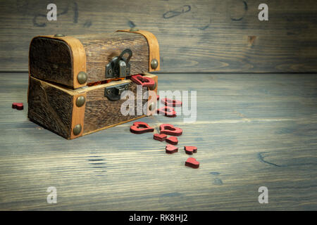 Herzformen Verschütten von einer Amtsleitung oder Schatztruhe auf ein altes rustikales Holz- Oberfläche mit Kopie der Platz in einem konzeptionellen Bild der Liebe und Romantik Stockfoto