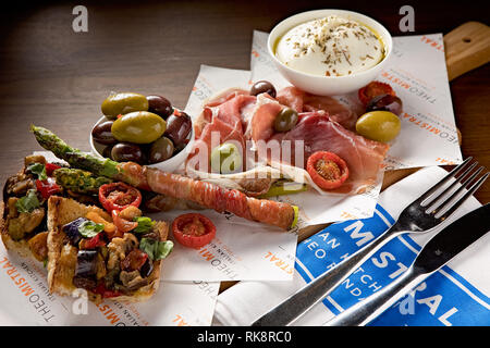 Frische Auswahl an italienischen Antipasti wie Oliven, geröstetes Brot mit Gemüse, cremiger Käse und Schinken Stockfoto