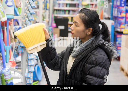 Einkauf von Reinigungsmittel in einem Kaufhaus. Junge Frau mit einem Besen in einem Shop. Stockfoto