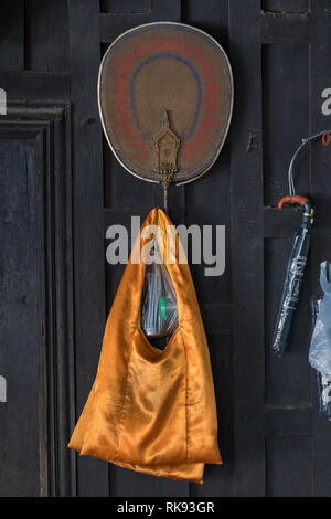 PHOTHARAM, Thailand, 02.Juni 2018, orange Tasche hängen an der Wand mit talipot Ventilator im buddhistischen Kloster Stockfoto