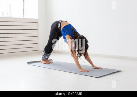 Gesunder Lebensstil, Menschen und Sport Konzept - junge Frau mit lockigem Haar Yoga auf weißem Hintergrund Stockfoto