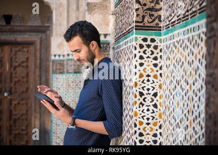 Junge muslimische Menschen in Freizeitkleidung lächelnd und Arbeiten auf Tablet im traditionellen arabischen Ambient Stockfoto