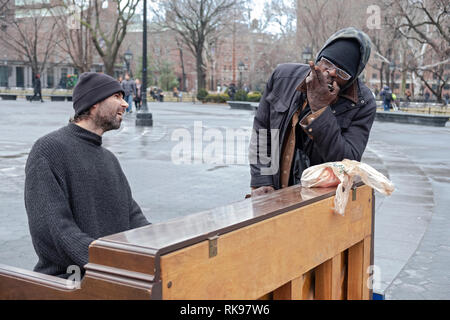 Ein Klavier spielen Gaukler führt mit einem Passanten bye Wer hat blues Duette mit ihm auf seiner Mundharmonika. Im Washington Square Park in Manhattan, New York City. Stockfoto