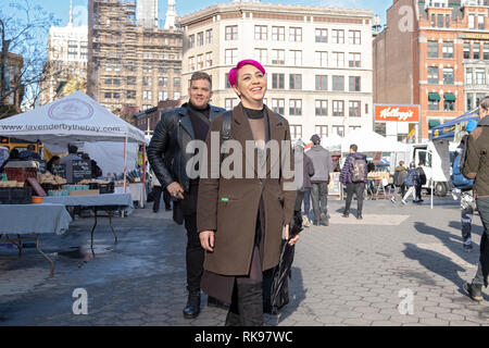 Ein junger Mann und eine Frau, offenbar ein Paar, Spaziergang durch Union Square Park in Manhattan mit einem breiten Lächeln. Stockfoto